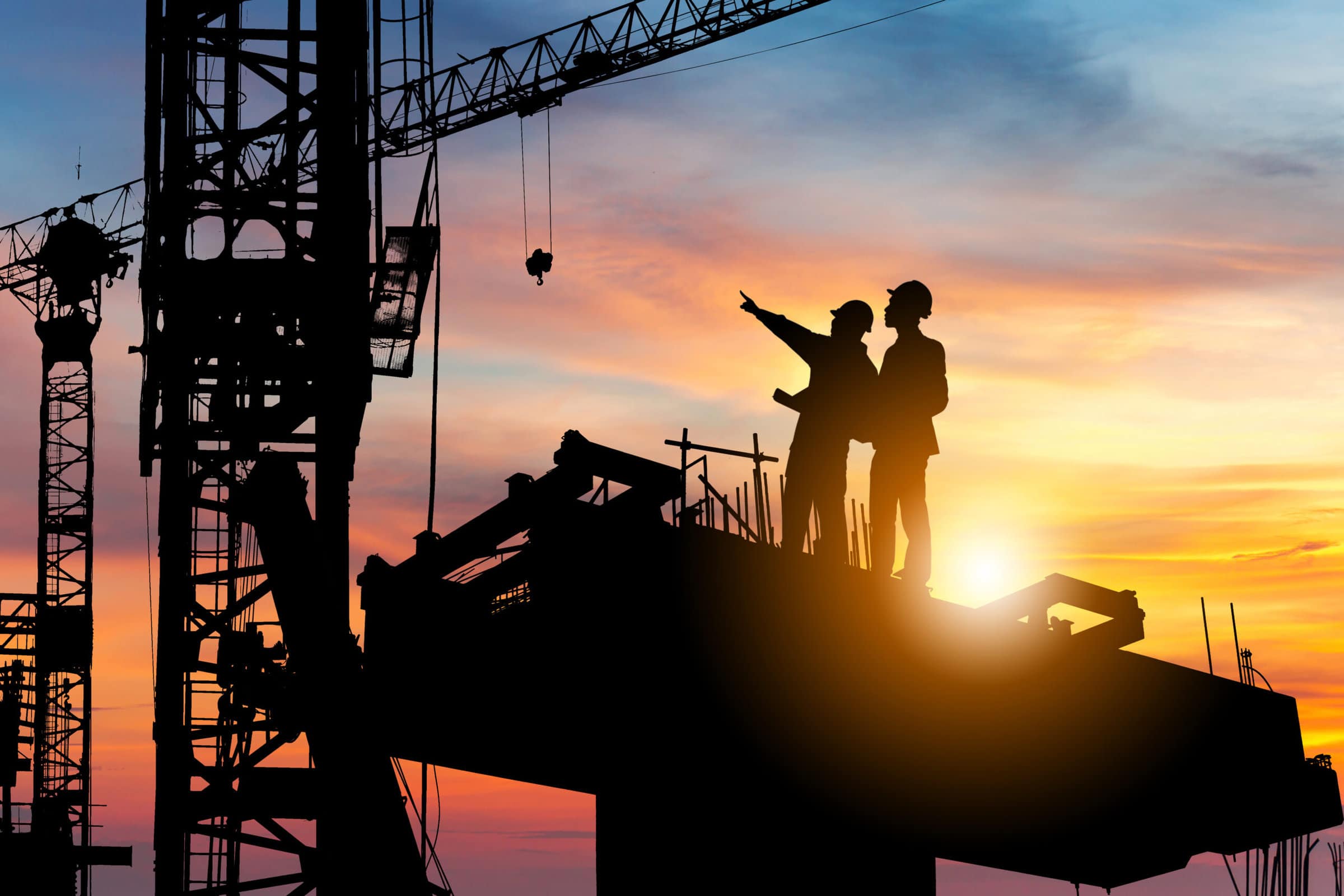 Silhouette,Of,Engineer,And,Worker,Checking,Project,At,Building,Site Silhouette of two men, working in twilight on top of a skyscraper
